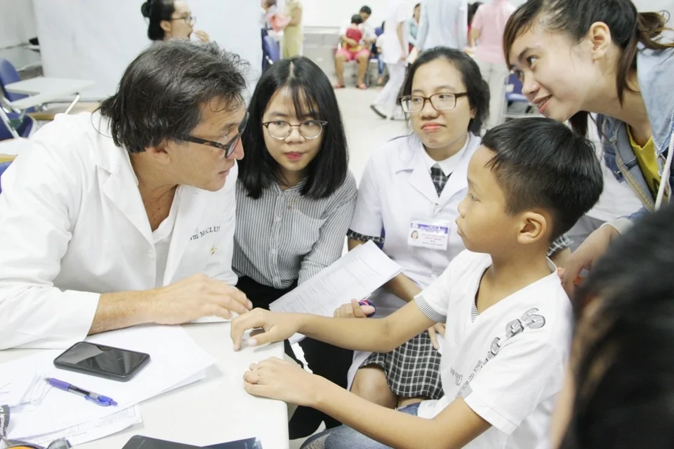 BS William Mc Clure, Trưởng đoàn Resurge International (Hoa Kỳ) khám cho bệnh nhi bị dị tật