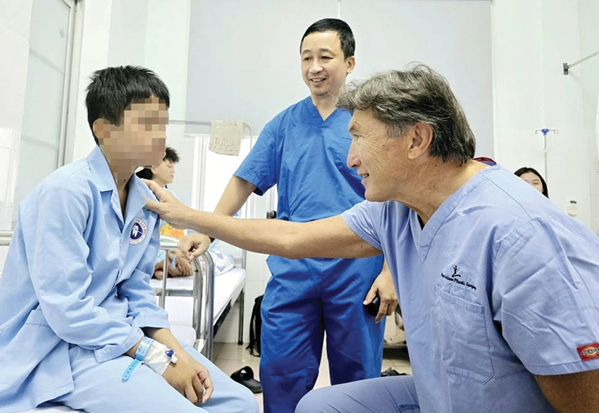 GS. William J. McClure, Trưởng Đơn vị Phẫu thuật tạo hình - Thẩm mỹ Tổ chức ReSurge International thăm hỏi, động viên sức khỏe cháu L.V.T.A. sau khi thực hiện thành công ca phẫu thuật tạo hình